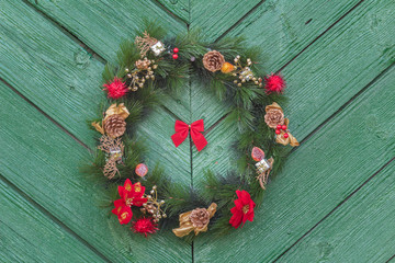 Outdoor hanging Christmas adorn wreath at old green wooden door