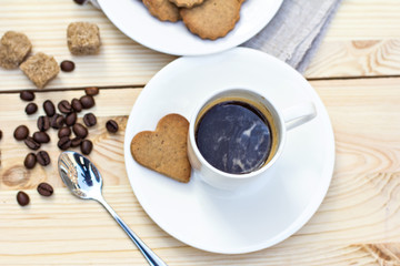 Ginger biscuits, cinnamon, a cup of hot coffee. Walnuts, hazelnuts on a wooden background