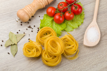 Pasta, tomatoes and pepper on a wooden background