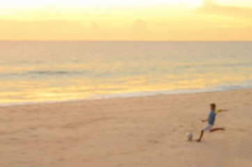 Blur boys playing football on beach abstract background.