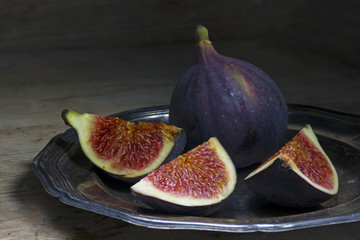 figs on an old silver plate on a rustic wood, dark background