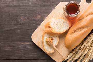 Rustic bread or baguette with honey on the wooden background