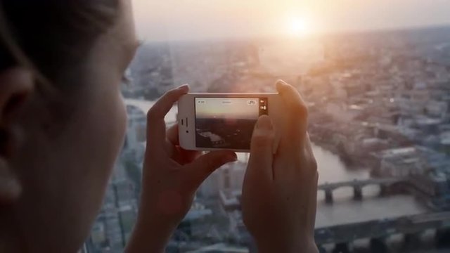 Tourist taking photograph sunset london skyline mobile phone view from The Shard