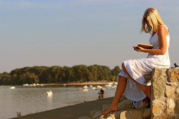Fototapeta premium Woman reads a book on the river