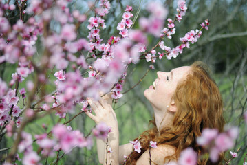 beautiful red-haired girl among the flowering trees