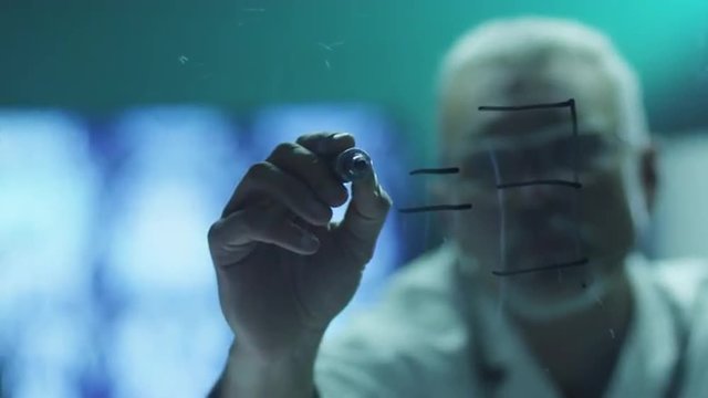 Scientist is Drawing Einstein's Mass-Energy Equation with Marker on Glass.