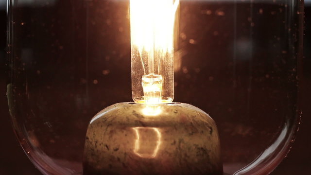 An old light bulb flashes on and of, close up, time lapse