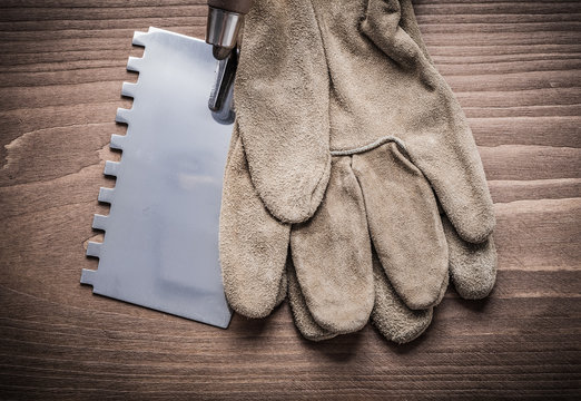 putty spattle and safety glove on wood board