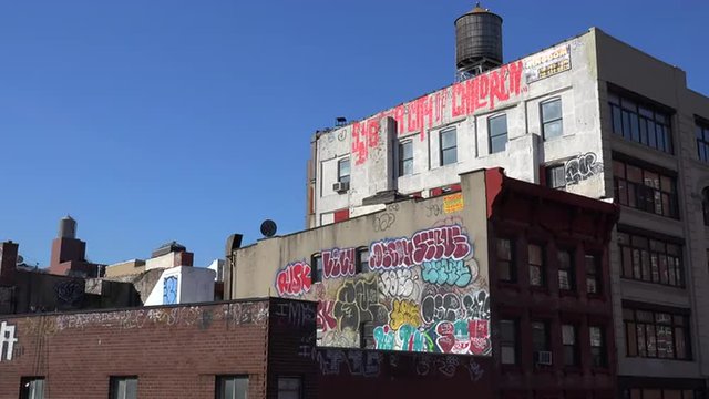 Graffitti art appears on the side of a building against the skyline in New York City.