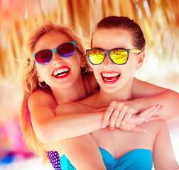 two beautiful young girls having fun on beach during summer vaca