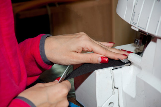 Sewing Process Woman's hands and blacke piece of cloth behind the sewing machine