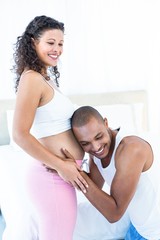 Man listening to belly of happy pregnant wife 