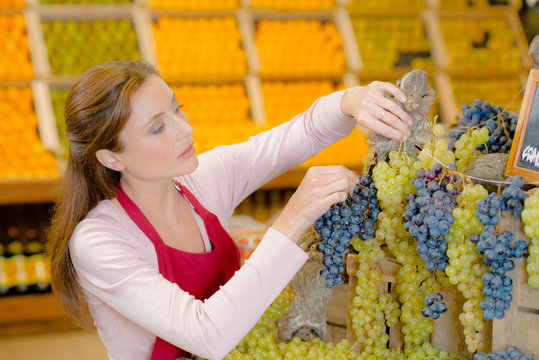 Shop assistant displaying grapes