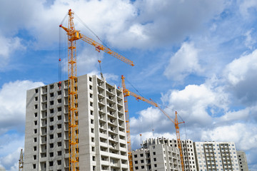 Fototapeta na wymiar Hoisting cranes and multi-storey housing under construction