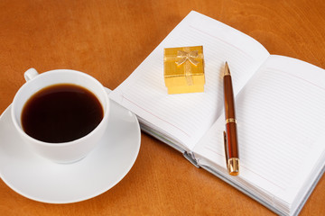Personal planner with gift box, pen and cup of coffee