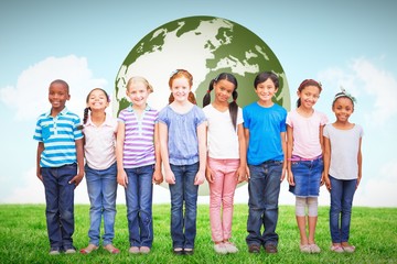 Composite image of cute pupils smiling at camera in classroom