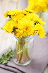 Yellow dandelion in bottle on grey wooden background