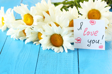 Obraz premium Chamomile flowers on a blue wooden background