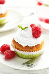 Raspberry cupcakes on plate on white wooden background