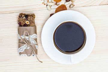 Fototapeta na wymiar Homemade rustic granola bars with dried fruits and handmade packaged and cup of coffee on wooden background
