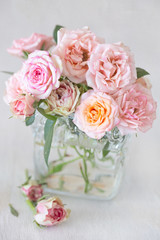 Beautiful fresh pink roses in a vase on a table .light background.