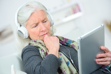 Fototapeta premium Senior lady listening to music through headphones