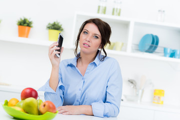 Junge Frau mit Mpbiltelefon in Küche
