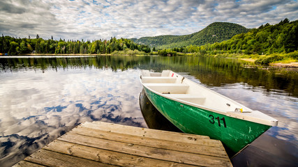 Boat by deck on a lake in National Park Mont Tremblant, Quebec, Canada. Nature, travel, explore, adventure, vacation, summer, north america, wilderness, retirement, fishing concept. Widescreen 16:9