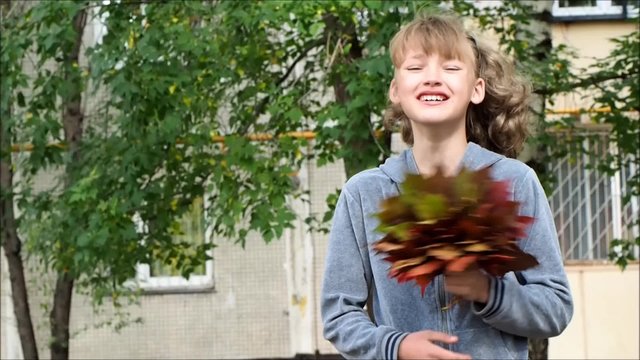 Портрет смеющейся девочки с букетом осенних листьев клена