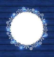 Christmas round frame made in snowflakes on blue wooden backgrou