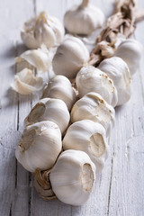 plait of white garlic on white wooden background