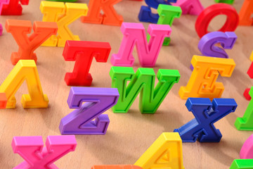 Plastic colorful alphabet letters on a wooden background
