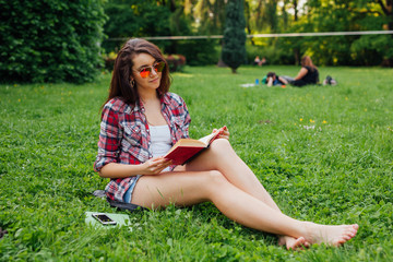 Brunette woman sitting in the park and reading book.