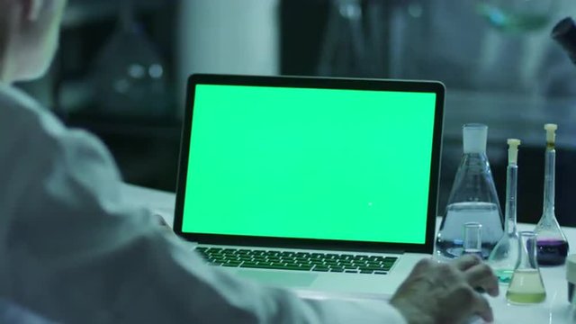 Scientist is using Laptop with Green Screen in Laboratory. Great for Mock-up Usage.
