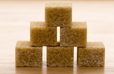 Brown cane sugar cubes on wooden background.Macro