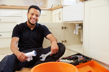 Mixed race plumber sitting in a kitchen, portrait © Monkey Business