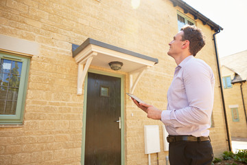 Male real estate agent looking up at a house exterior