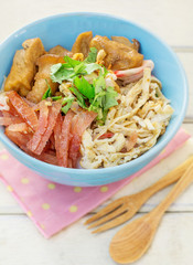 Chinese rice noodle roll with egg, chinese sausage, tofu (Kuay Teow Lod)  on blue bowl and white wood table