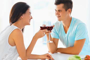 Portrait of couple clinking their glasses of red wine in the kit