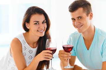 Couple smiling at the camera with red wine. Celebration