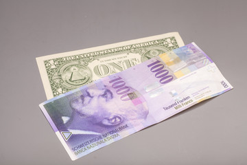 American dollars and Swiss franc currency isolated on gray