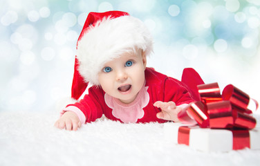 Beautiful little baby celebrates Christmas. New Year's holidays. Baby in a Christmas costume with gift