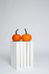 two bright orange pumpkins on a white crate