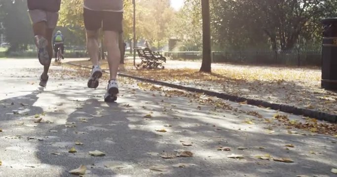 Group of runners running in park wearing wearable technology connected devices