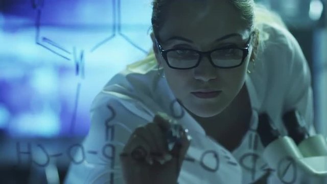 Woman Scientist is Drawing Organic Chemical Formulas on Glass. Shot on RED Cinema Camera in 4K (UHD).