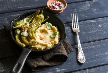 delicious vegetarian lunch - bean puree and spicy roasted peppers with garlic and herbs in a pan, on a dark wooden surface, rustic style
