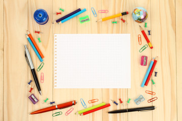 Naklejka premium Sheet of paper with school office supplies on wooden background