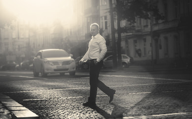 monochrome photo of businessman crossing road at sunny day