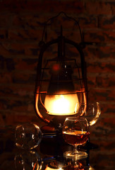Cognac in a glass on a background of a burning lantern..