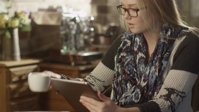Pretty Girl Typing on Tablet PC in Coffee Shop